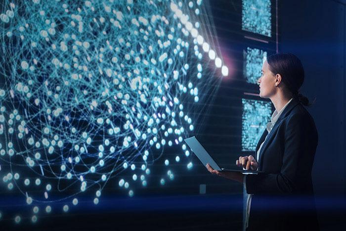 New AI Insights: Explore Key AI Trends and Risks in the ThreatLabz 2024 AI Security Report Woman holding laptop surveying large screen filled with constellation of data points