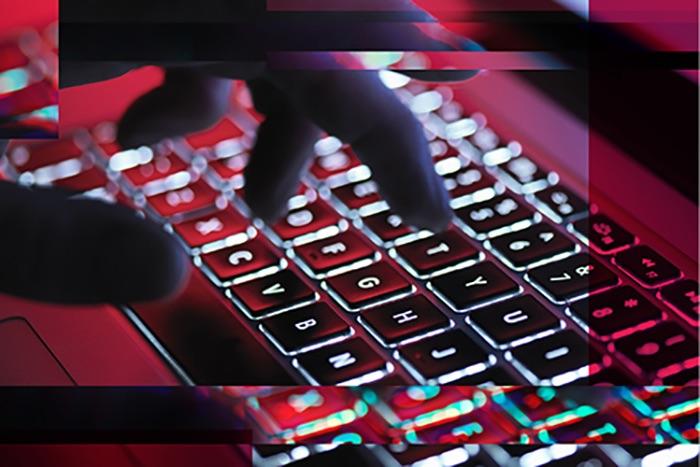 Autore di ransomware che digita su una tastiera Autore di ransomware che digita su una tastiera