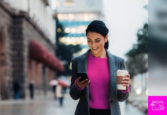 A woman standing in a city looking at her phone that is secured with zero trust