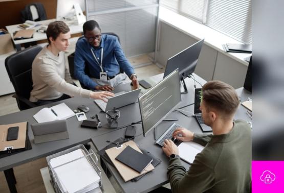 Three team members engaged with computers in an office, concentrating on malware incident response and solutions.