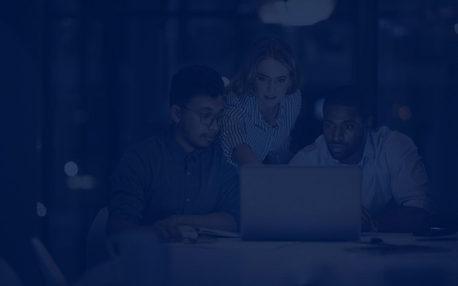 Three individuals engaged in a discussion while viewing a laptop in a meeting room, focusing on Zscaler Data Fabric for Security.