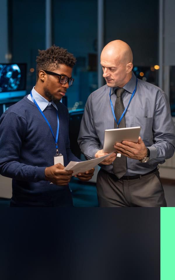 Two men in suits stand side by side, holding a tablet, symbolizing collaboration in threat exposure management.