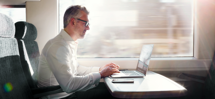 Man working on his computer while riding a train