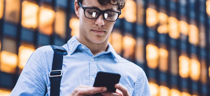 Hombre revisando su teléfono fuera del edificio